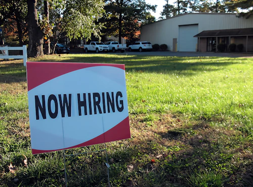 a now hiring sign in front of a building