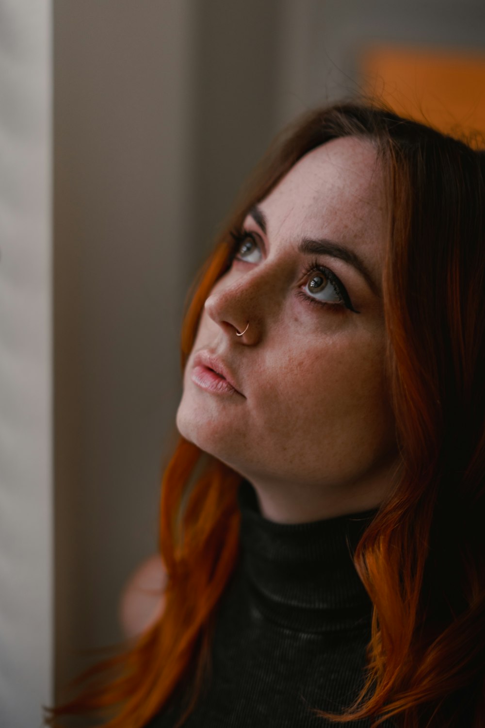 a woman with red hair looking out a window