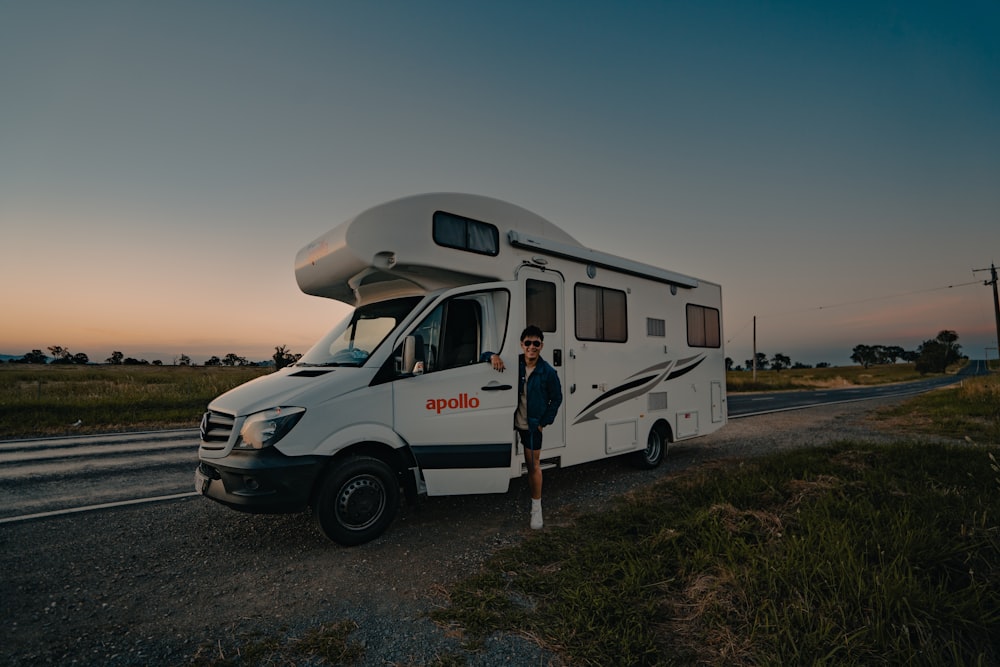 a man standing in front of a camper on the side of the road