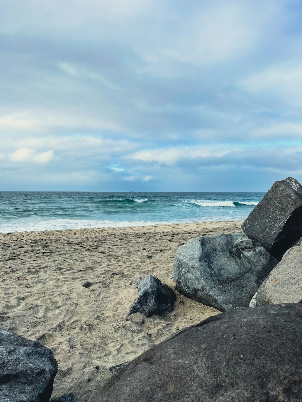 una grande roccia seduta sulla cima di una spiaggia sabbiosa