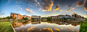A panoramic view of a luxury waterfront development at sunset, reflecting golden hues.