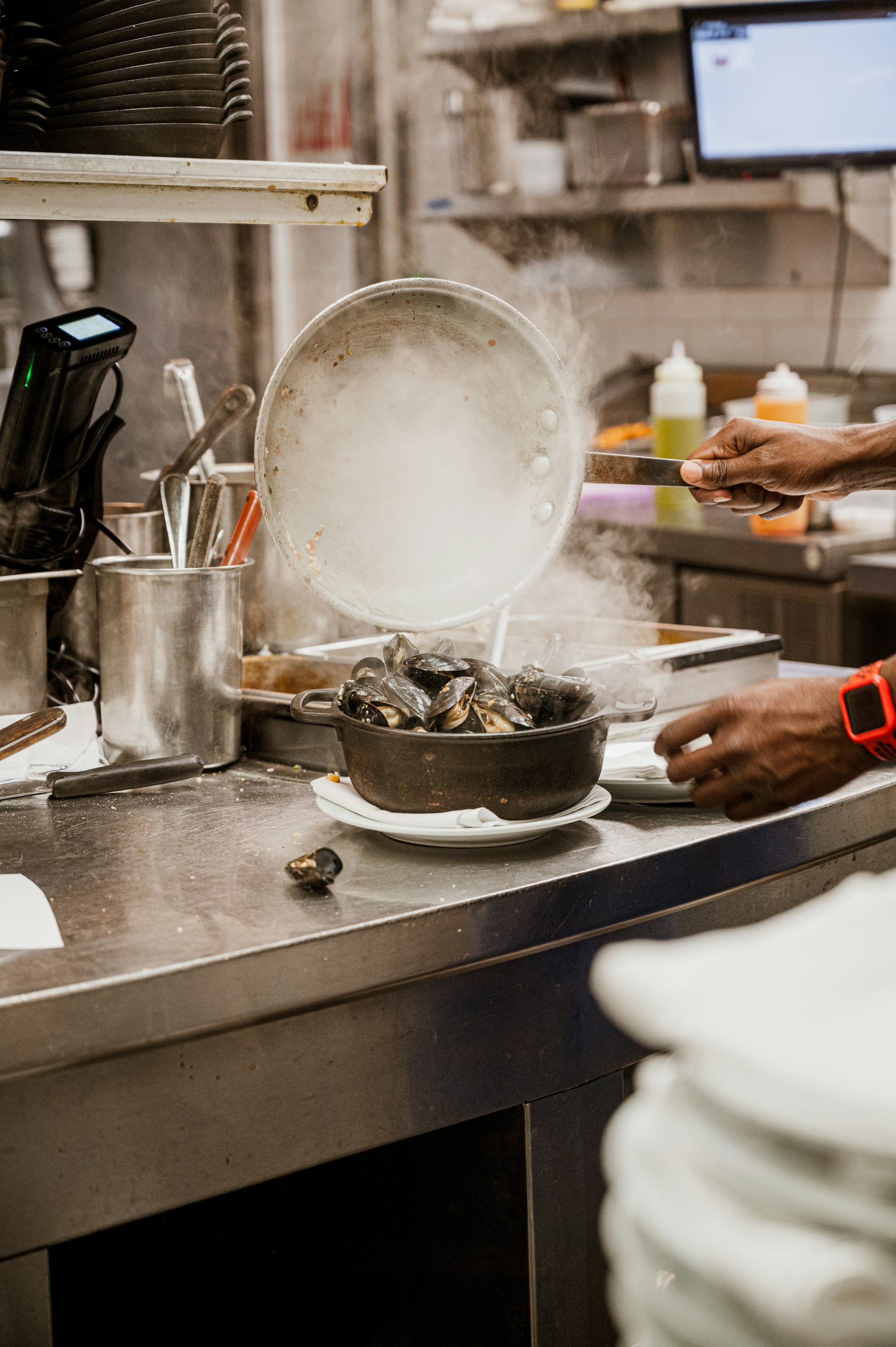 A lively kitchen scene showing hands preparing accras, with fresh herbs and spices scattered around.