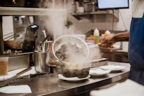 A professional chef preparing seafood in a modern kitchen illuminated with white and blue light.