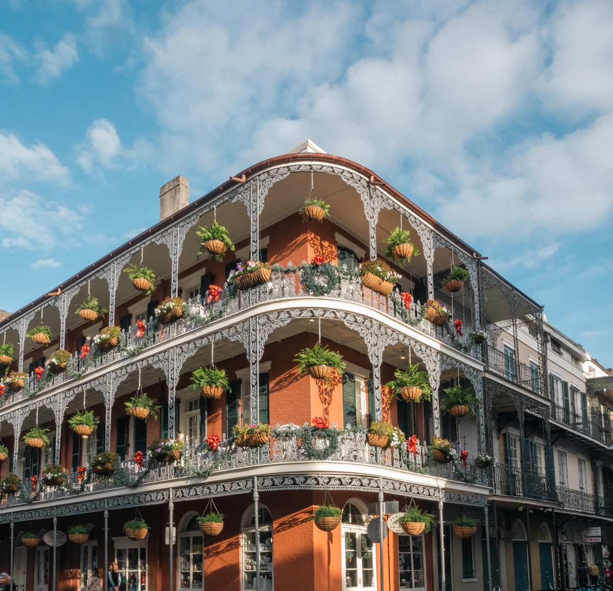 An ornate iron balcony filled with flowers on a historic New Orleans building