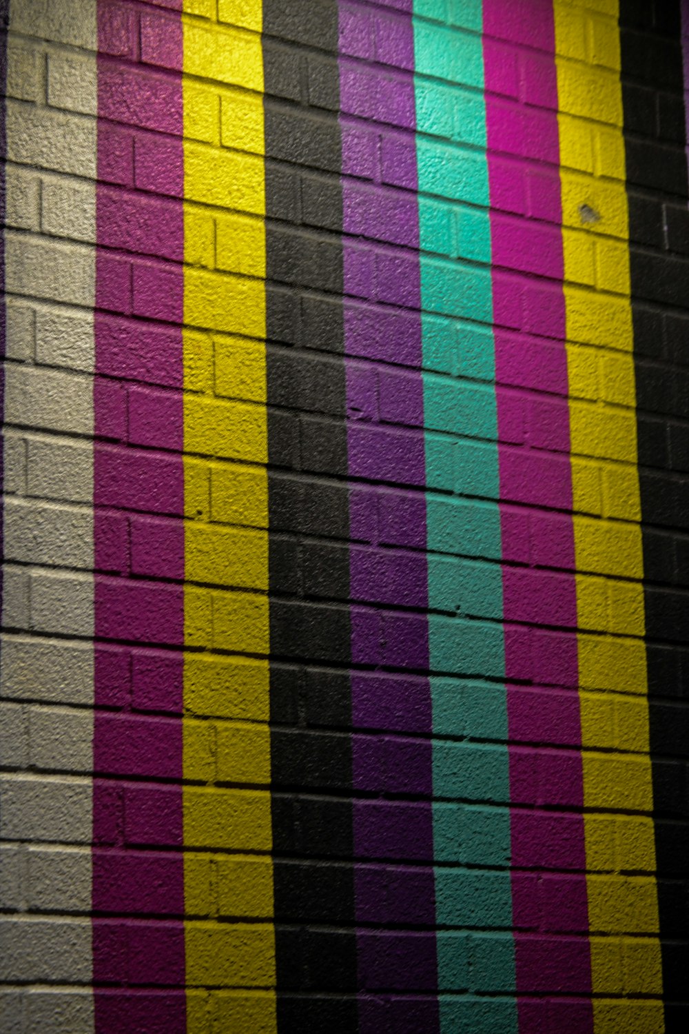 a brick wall painted with multicolored stripes