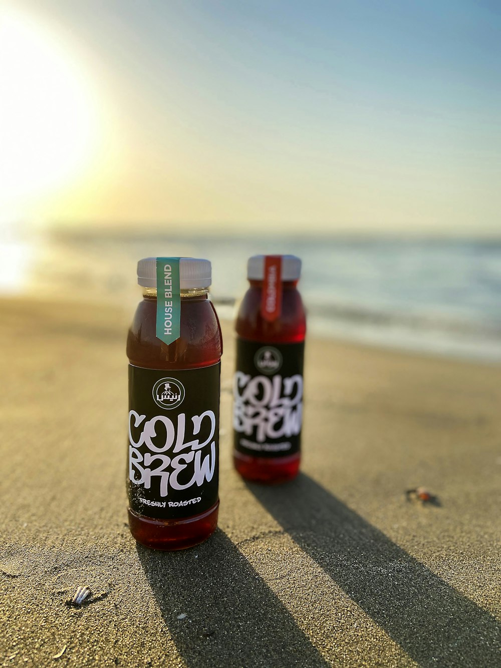 a couple of bottles sitting on top of a sandy beach