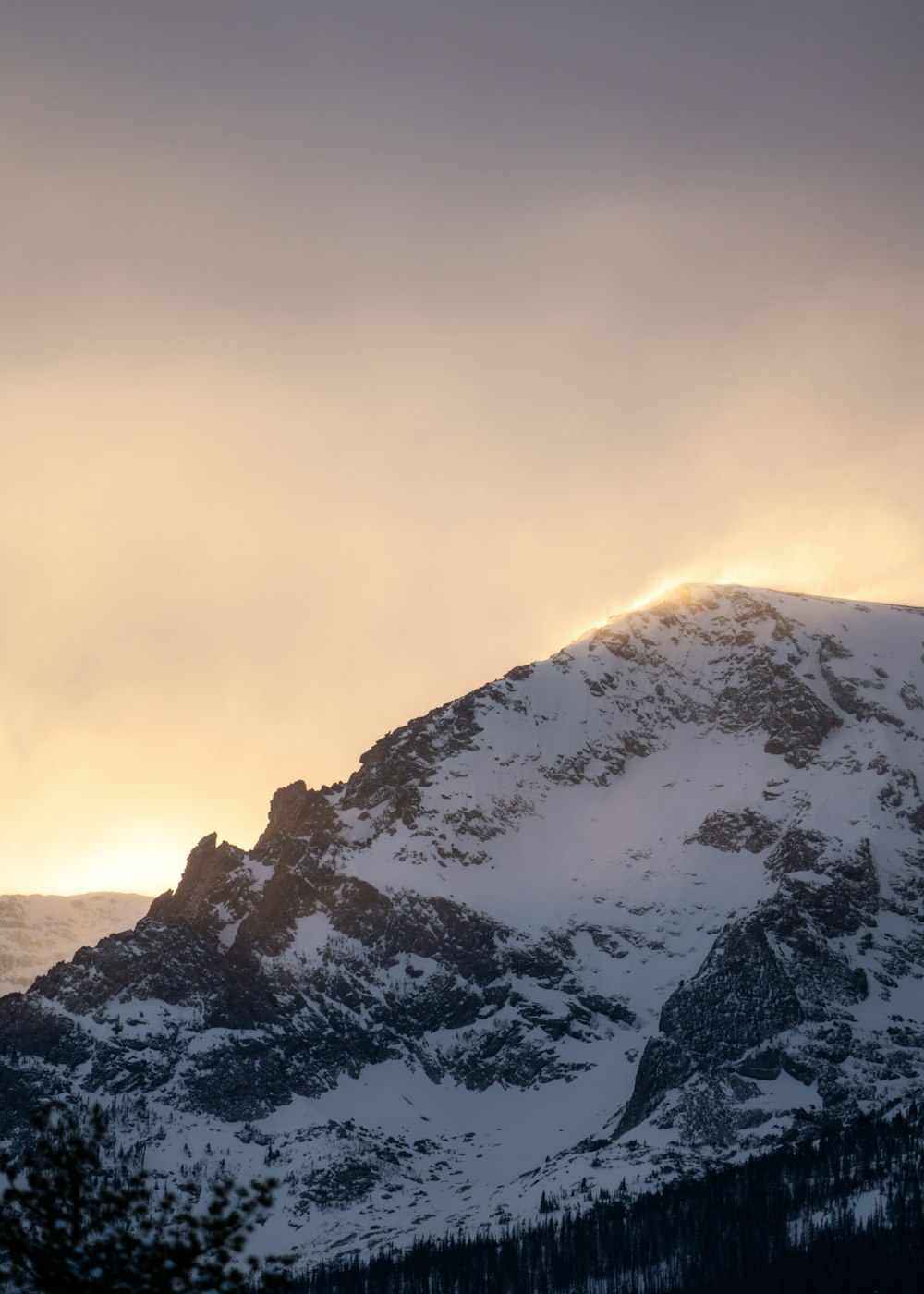 a mountain covered in snow under a cloudy sky