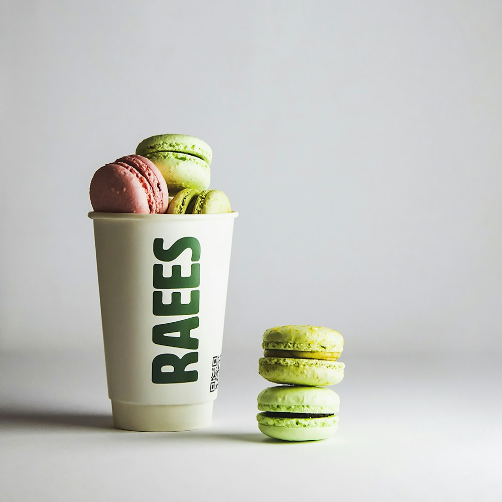 a cup filled with green and pink macaroons