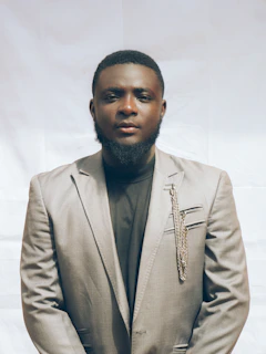 Model wearing a tailored gray blazer and crisp white shirt standing against a clean white wall