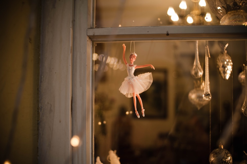 a ballerina in a white tutu is hanging from a window
