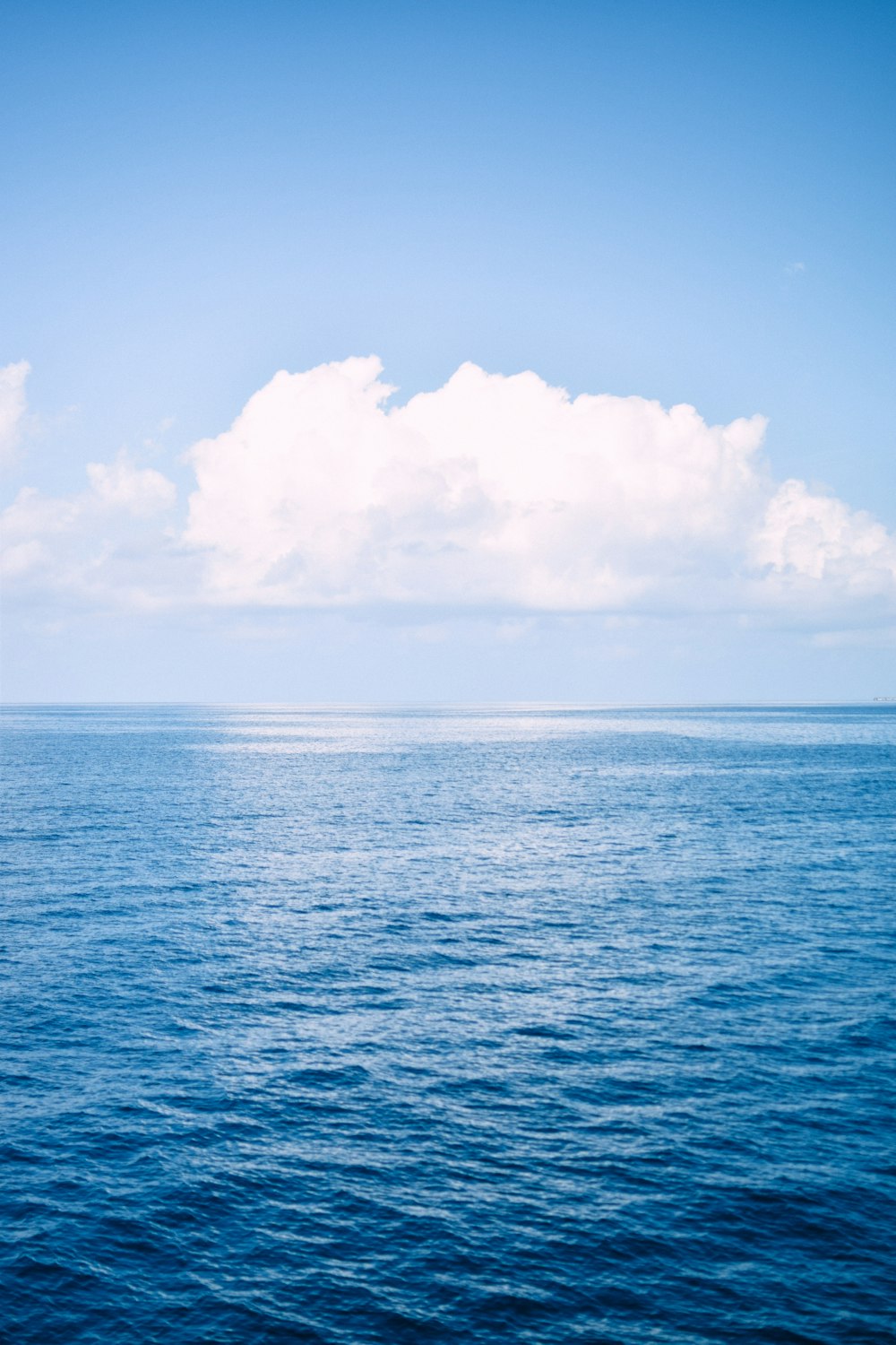 a large body of water under a cloudy blue sky