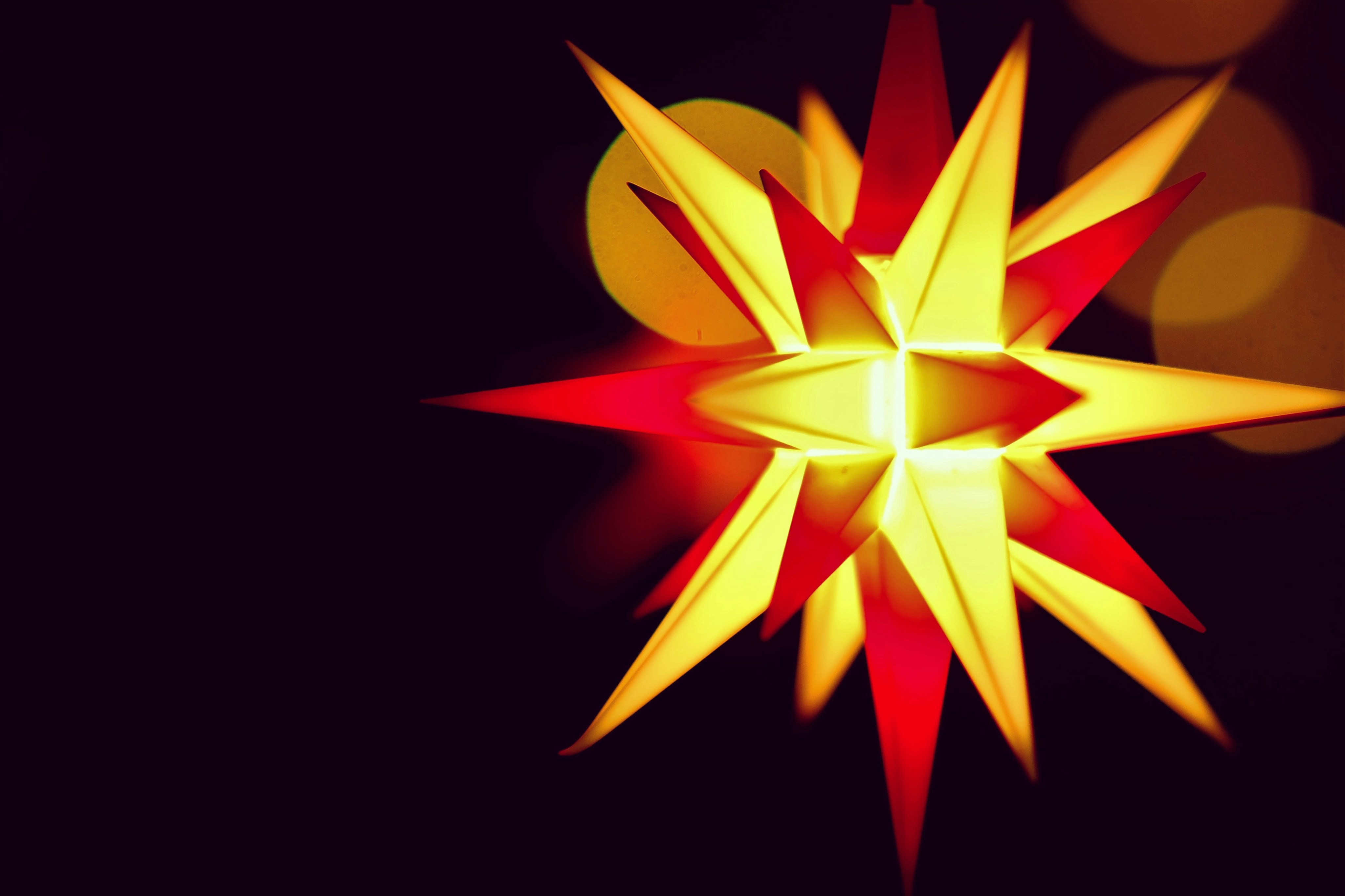 a red and yellow star ornament on a black background