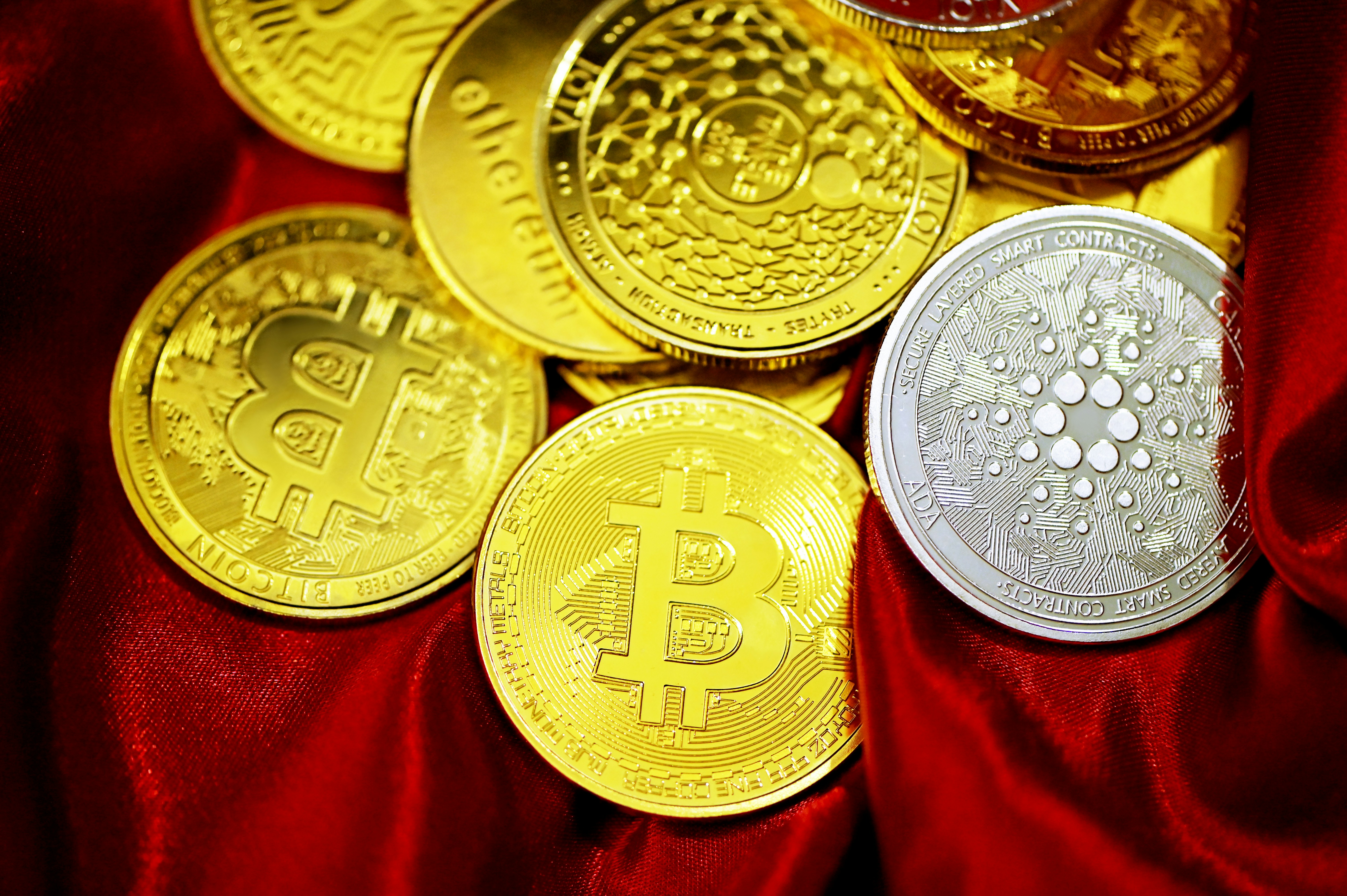 Scattered cryptocurrency coins on red velvet
