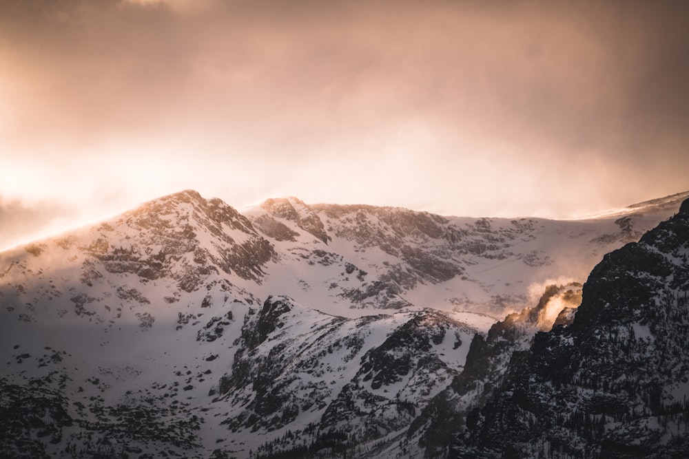 a snow covered mountain range under a cloudy sky