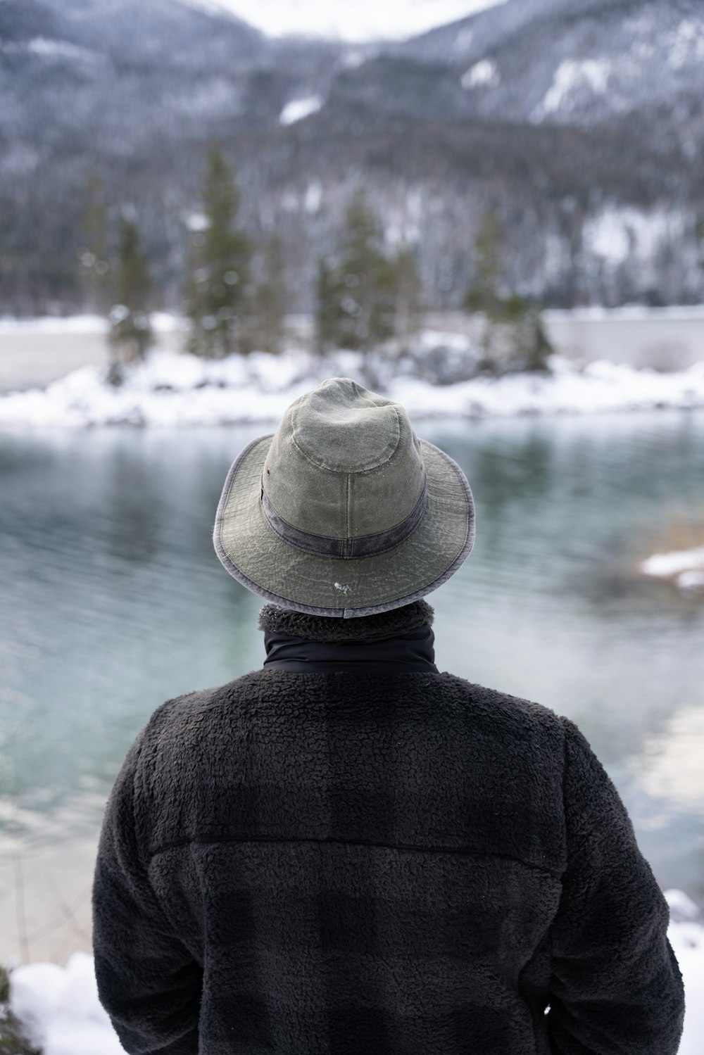 a man wearing a hat looking out over a lake