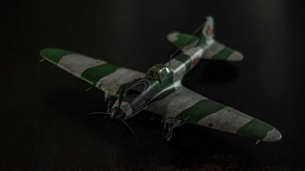 a green and white model airplane on a black surface