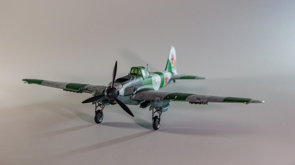 a green and white model airplane on a white surface