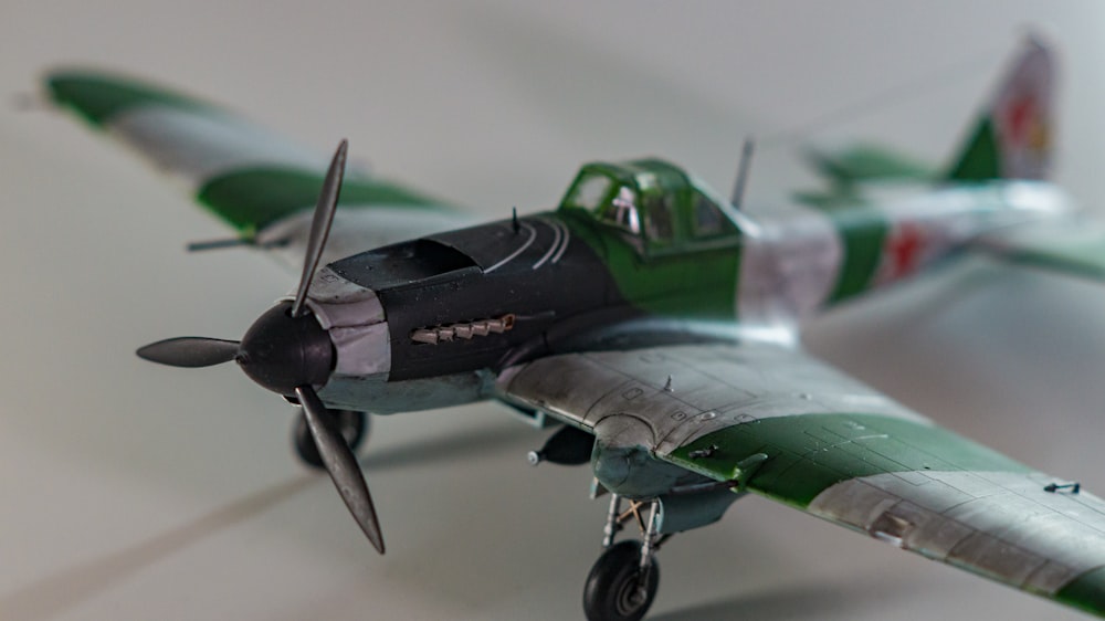 a green and white model airplane on a white surface