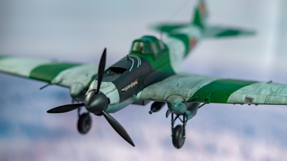 a green and white plane flying in the sky