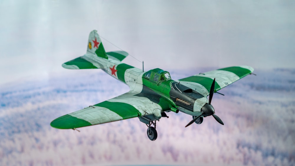 a green and white plane flying in the sky