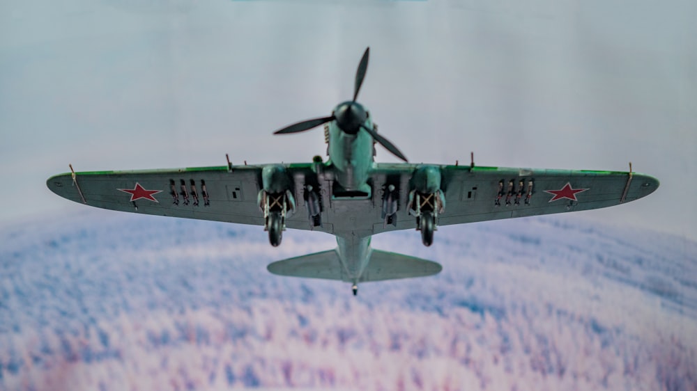 a military plane flying in the sky over a forest