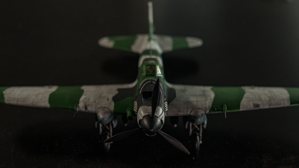 a green and white model airplane on a black surface