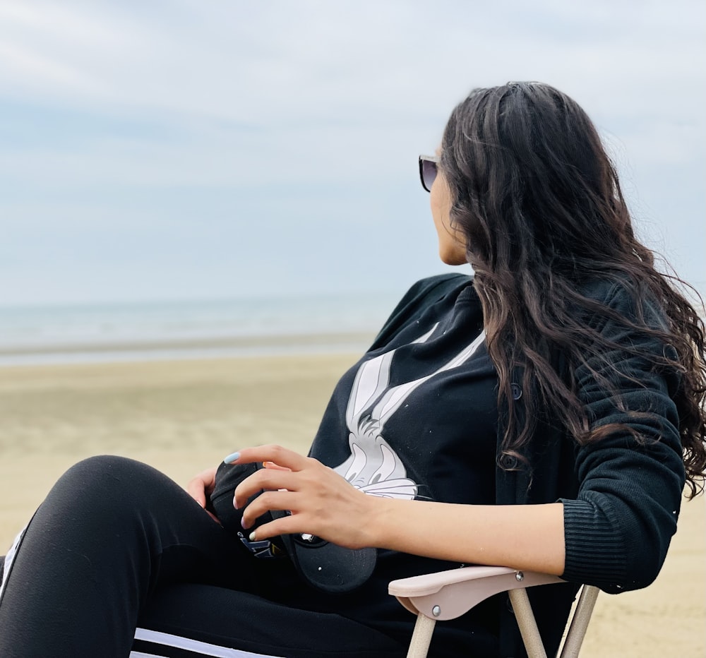 a woman sitting in a chair on the beach