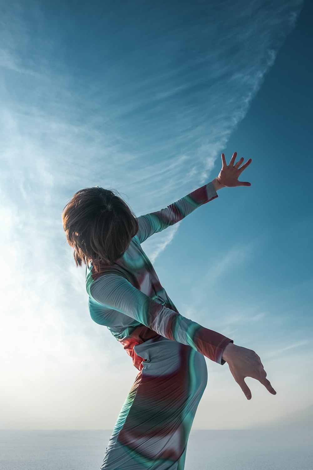 a woman in a colorful dress reaching for a frisbee