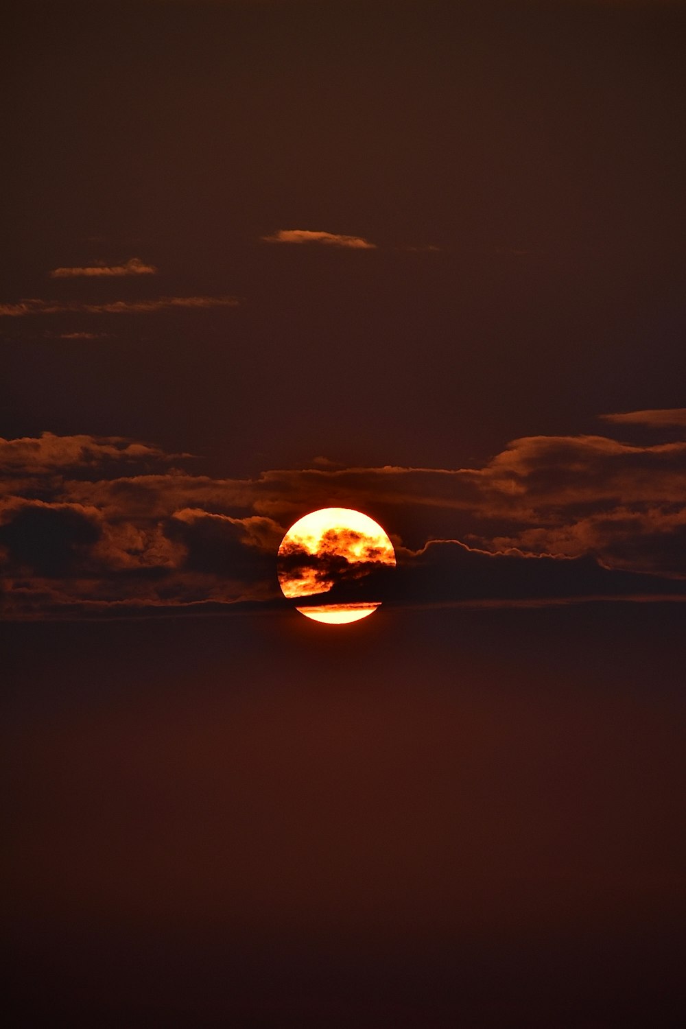 the sun is setting over the ocean with clouds