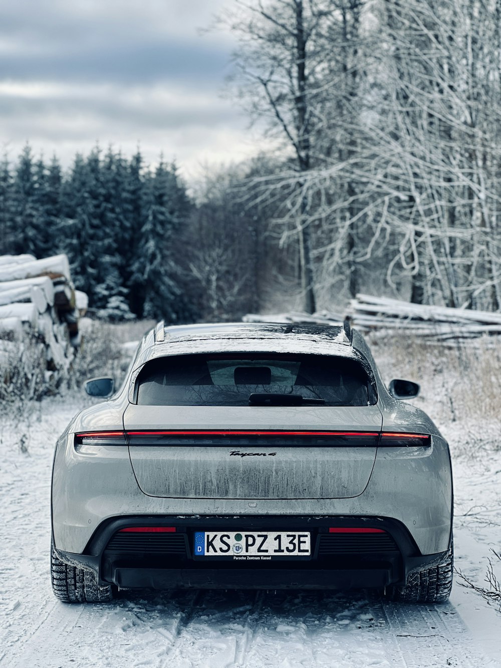 a car parked in the snow near a forest