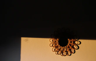 Close-up of a detailed macrame wall hanging casting soft shadows on a sunlit wall.