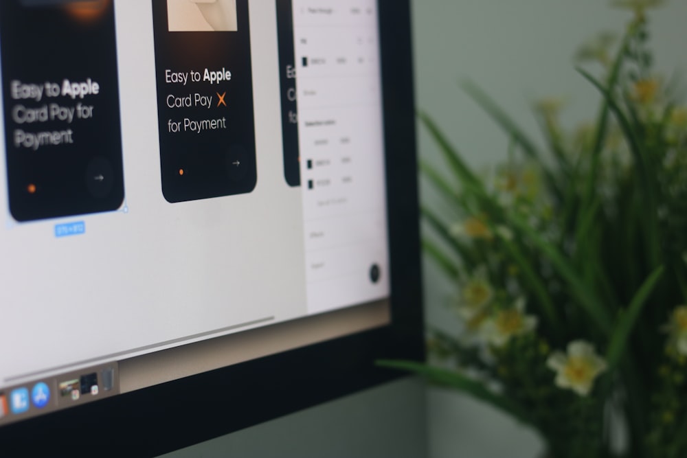 a computer screen with a vase of flowers in front of it