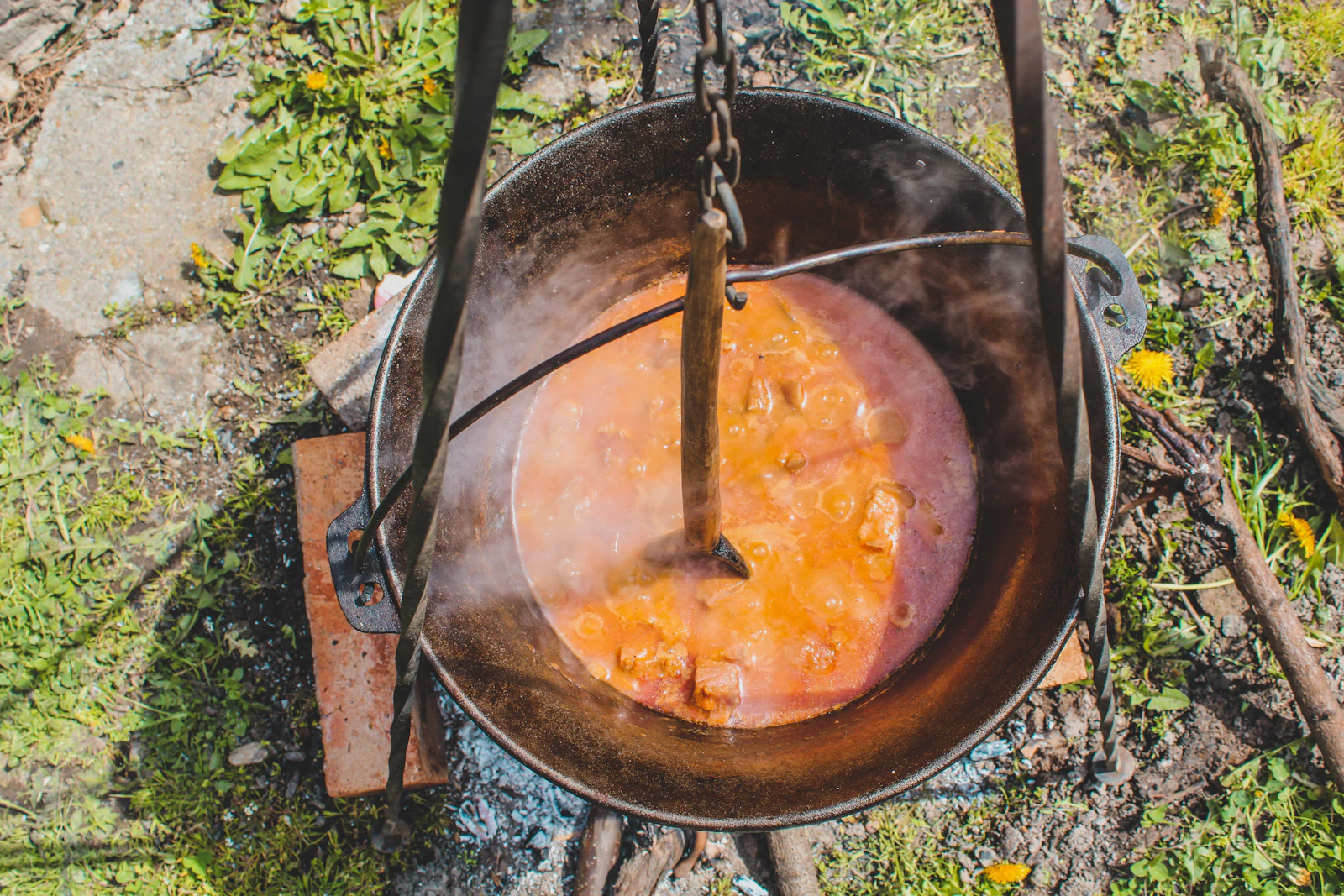 A pot of food cooking on an outdoor camp stove