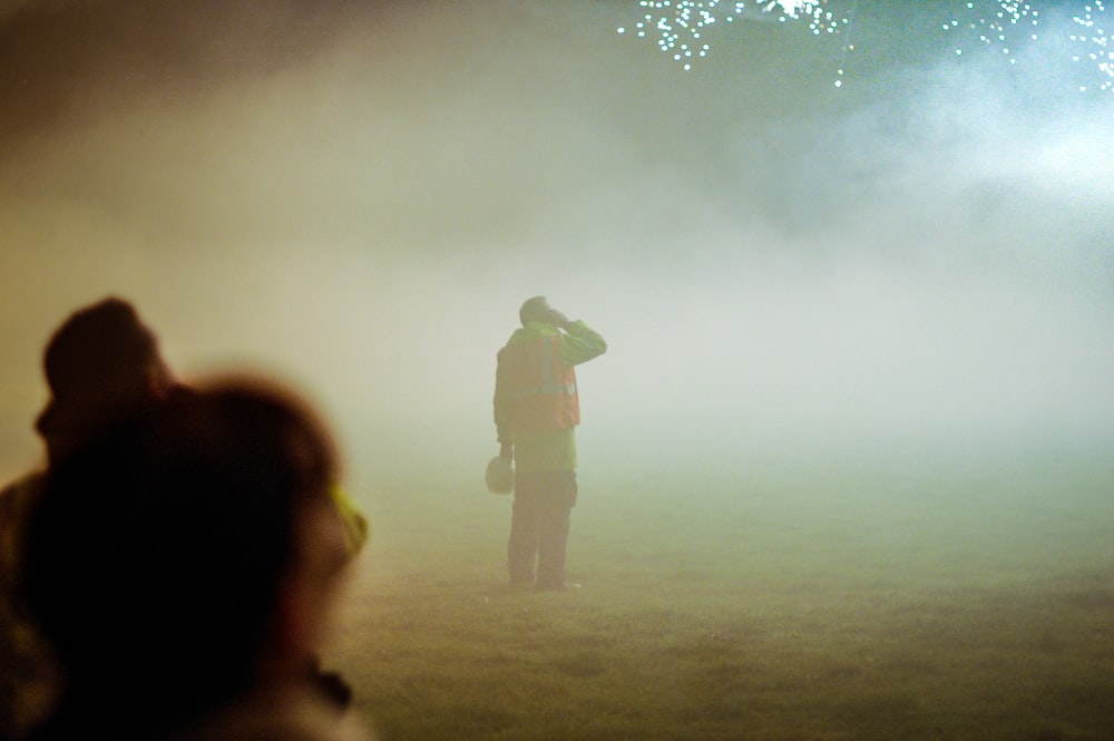 a person standing in a field with fireworks in the background