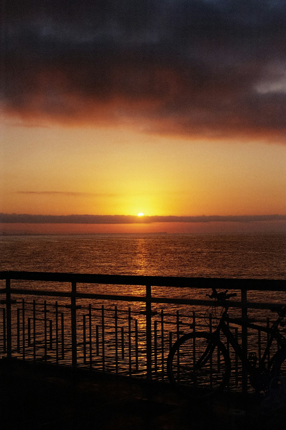 o sol está se pondo sobre o oceano em um dia nublado