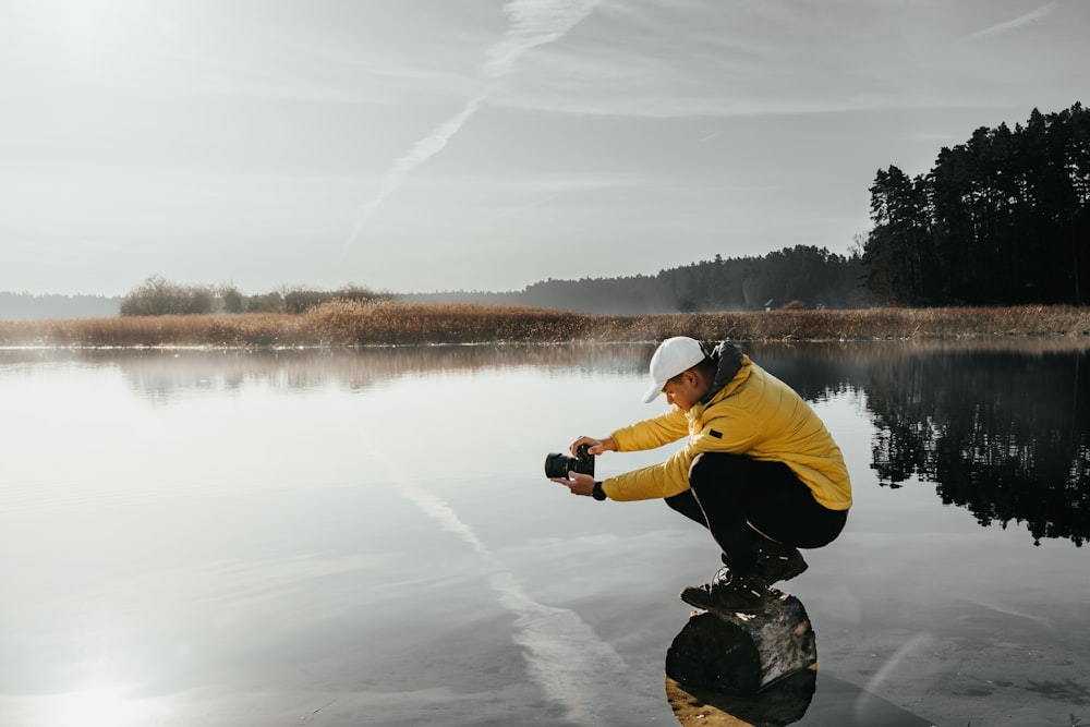 a man squatting on a rock in the water