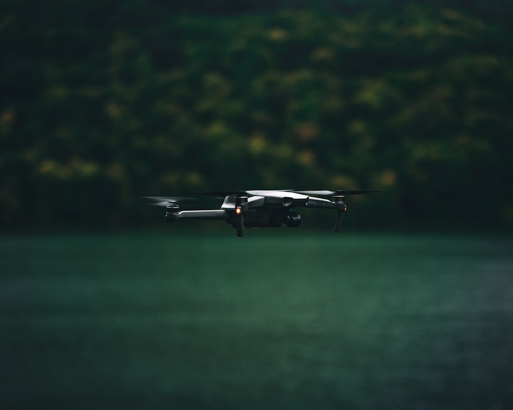 a black and white photo of a small plane flying over a body of water