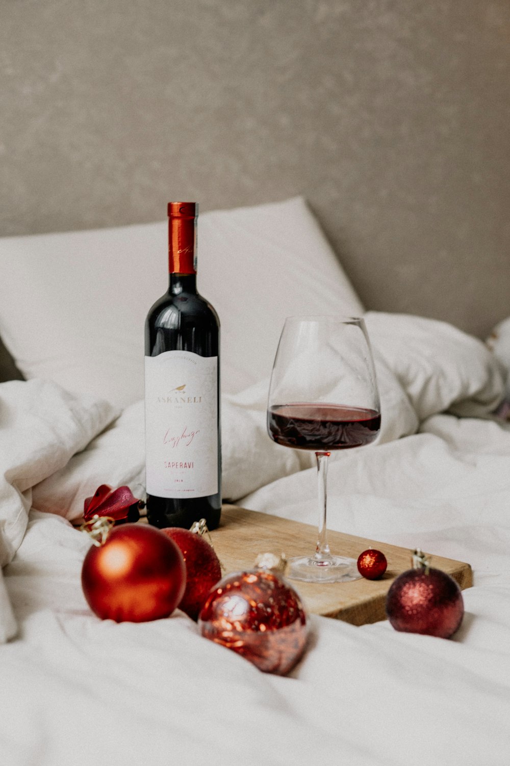 a bottle of wine and a glass of wine on a bed