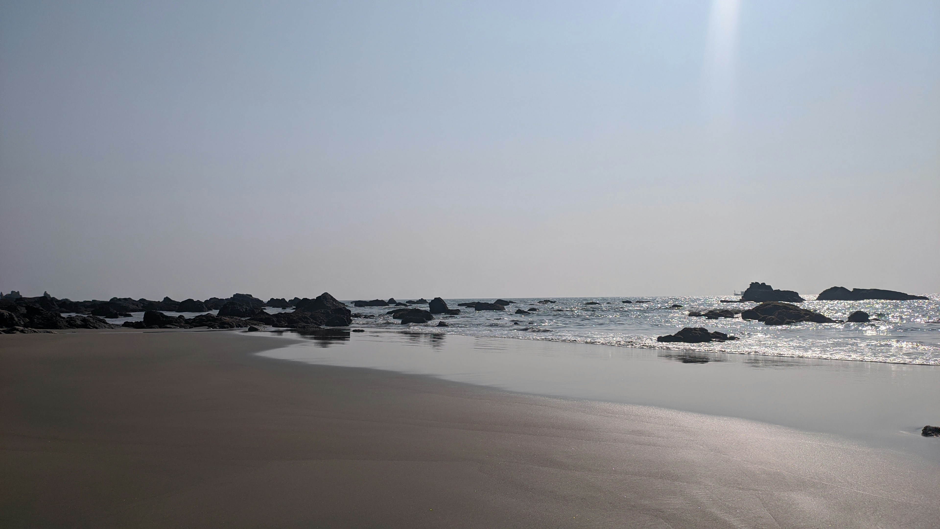 a beach with rocks and water on a sunny day, Kalacha Beach in Goa, India