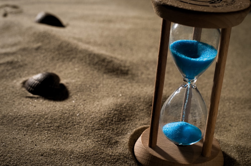 an hourglass with blue sand on a sandy beach