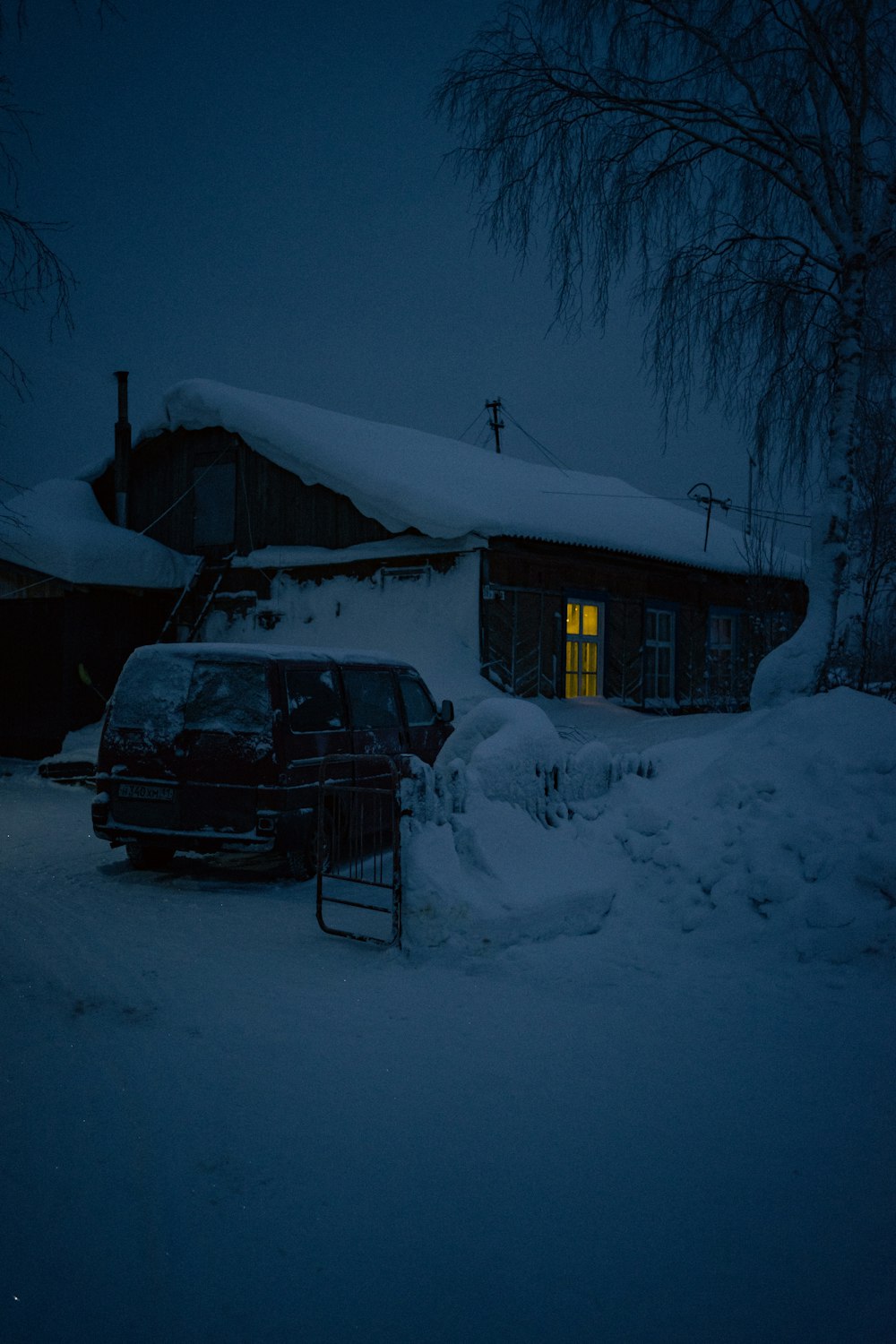 a car parked in front of a house covered in snow