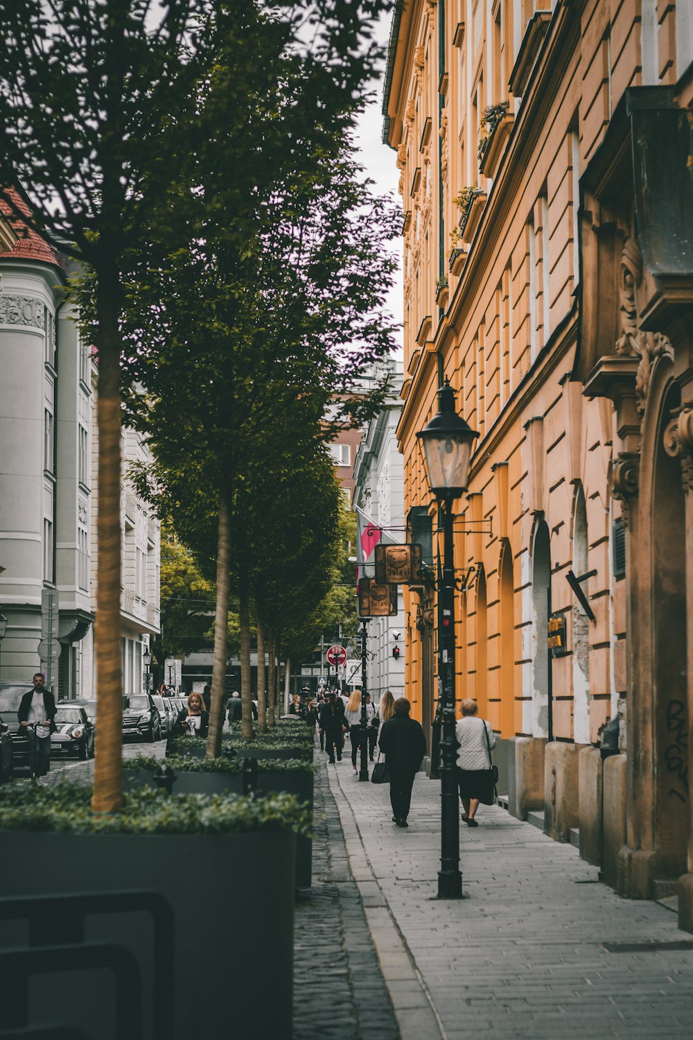 people walking down a sidewalk next to tall buildings