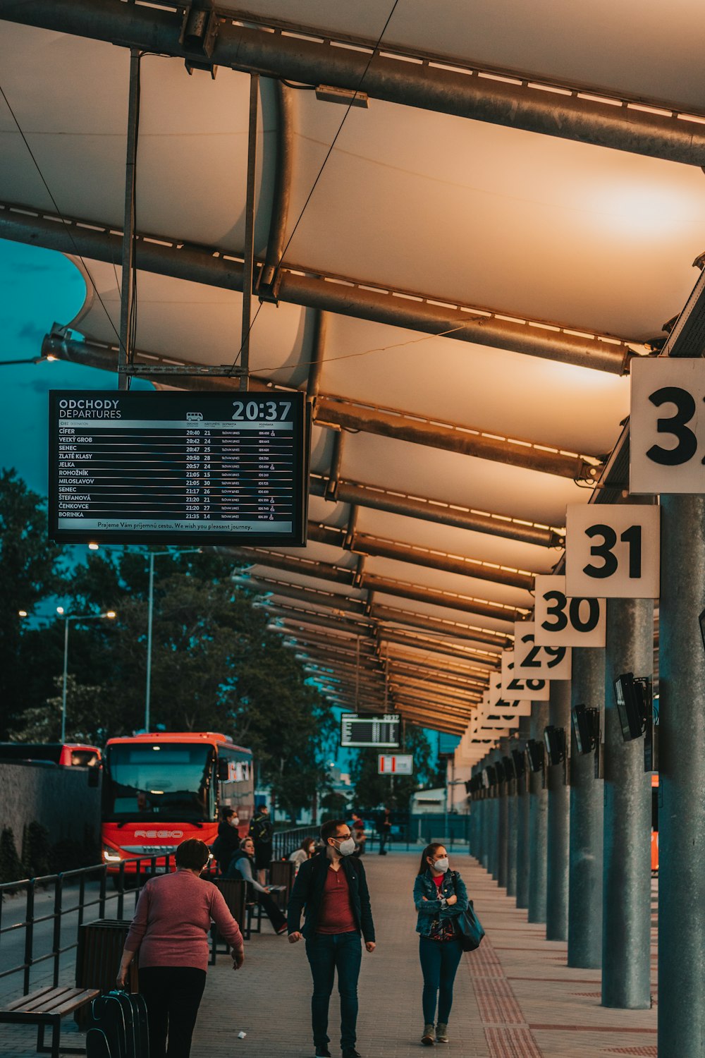 a group of people walking down a sidewalk next to a train station