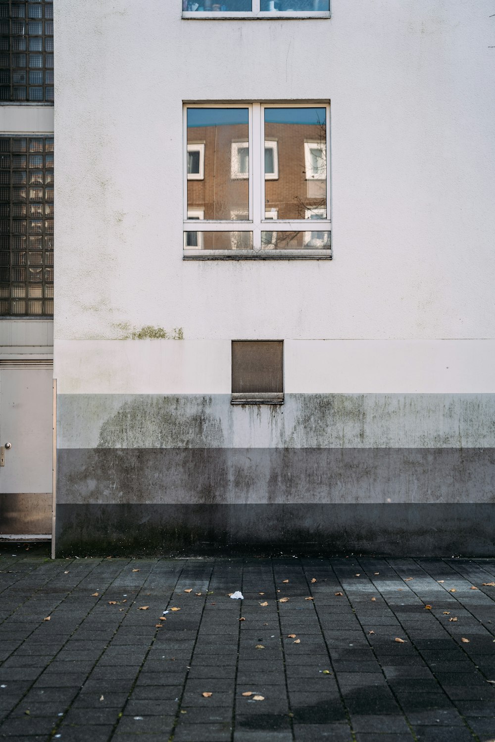 a white building with a window and a brick sidewalk