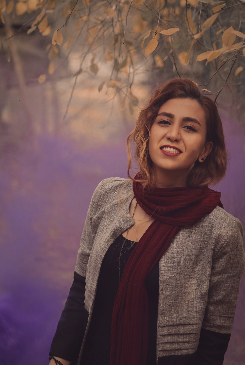 Une femme debout sous un arbre avec un foulard autour du cou