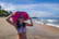 A joyful woman wearing a stylish Coraluz bikini on a sunny beach with soft golden sand.