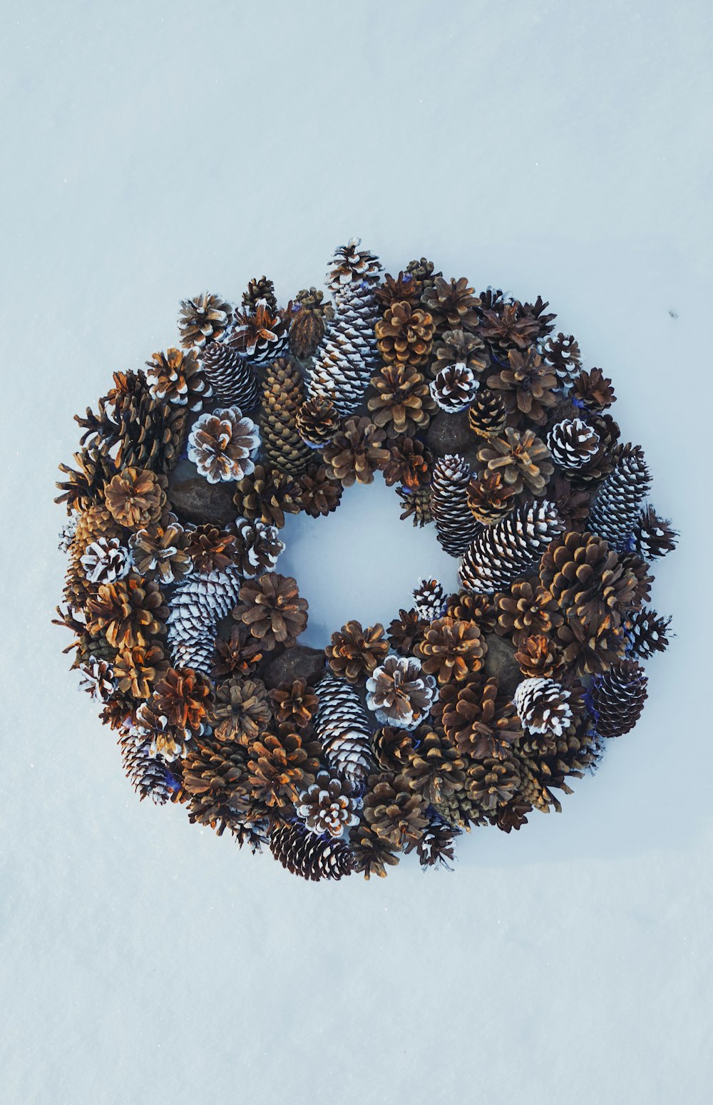 a wreath made of pine cones and cones in the snow