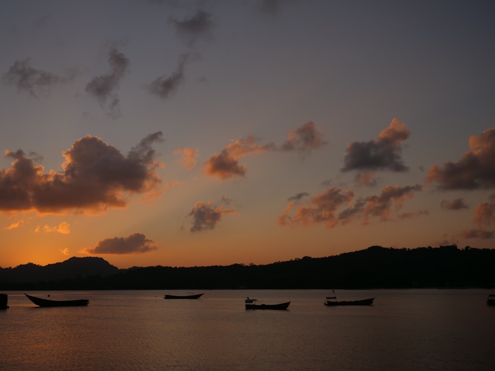 a group of boats floating on top of a lake under a cloudy sky