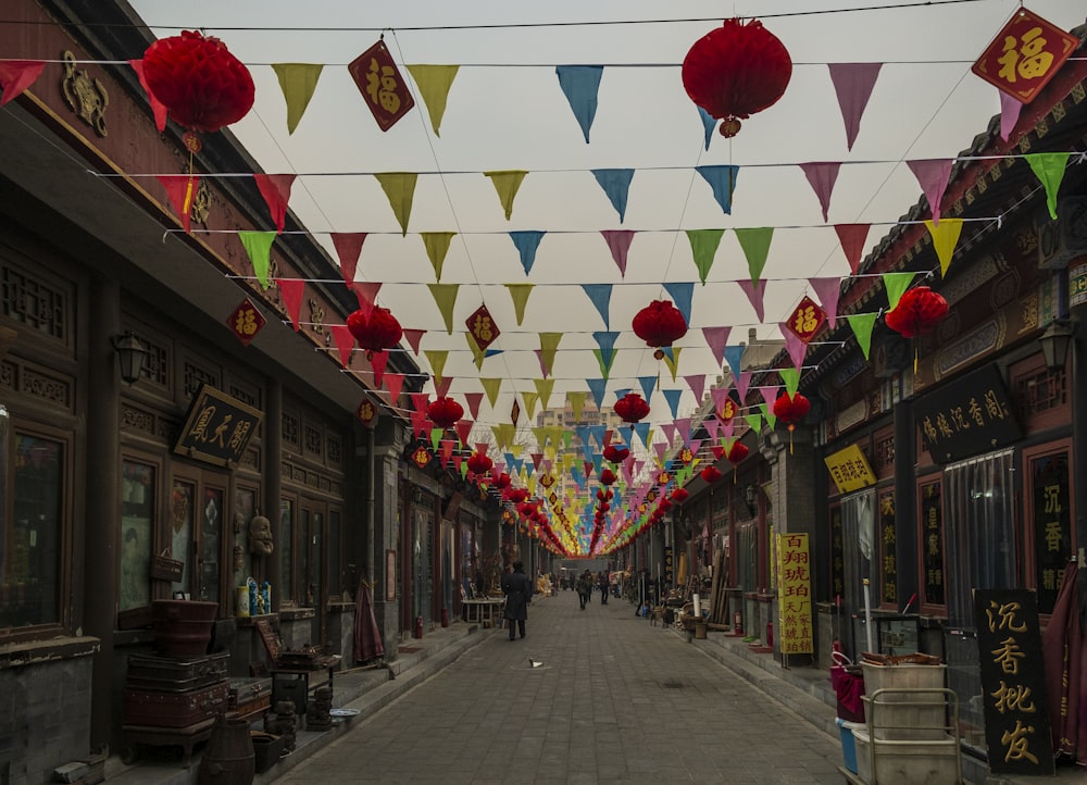 a street lined with lots of red, yellow, and green paper lanterns