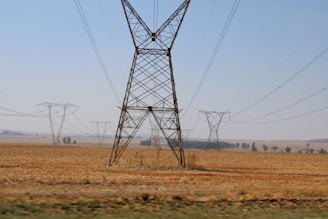 A panoramic view of electricity transmission lines stretching across Ontario's rural landscape under a clear sky.